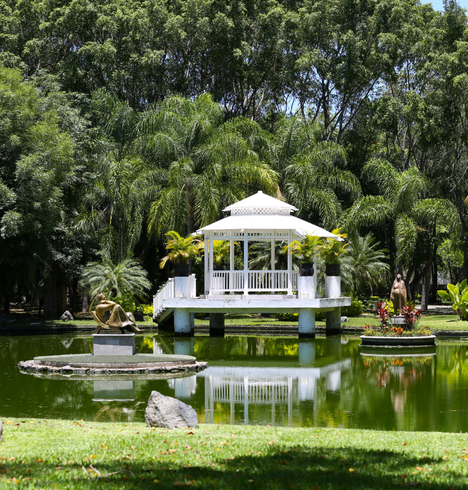 Kiosco blanco reflejado en el lago rodeado de jardines