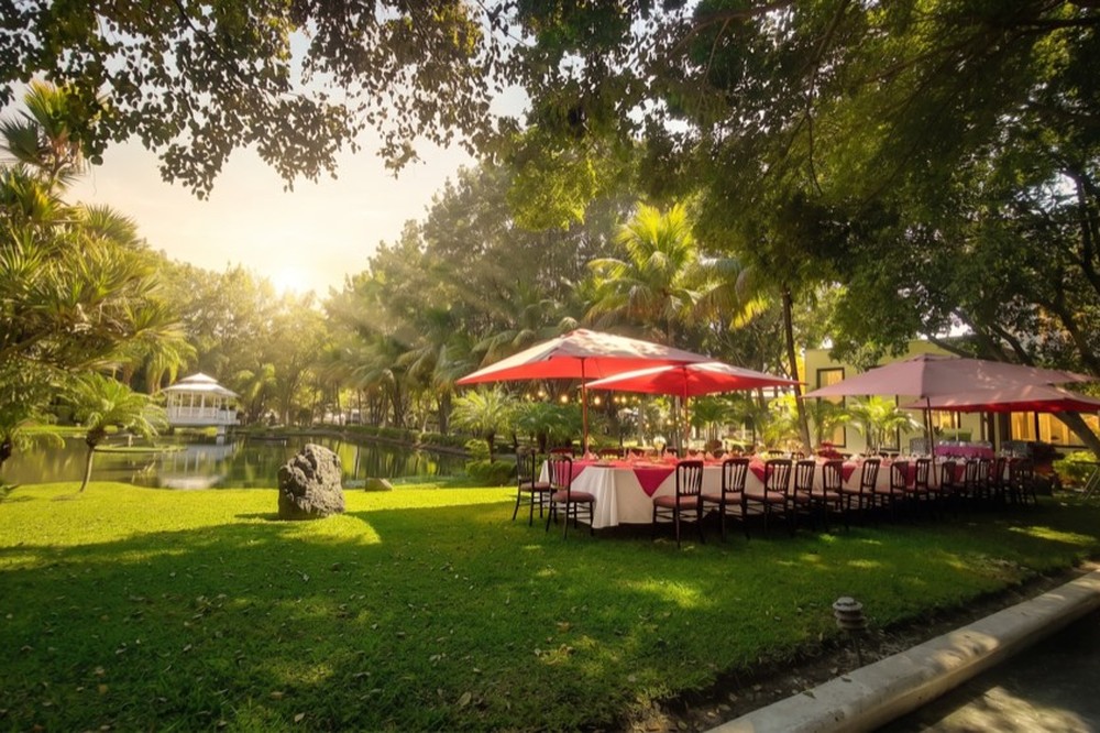 Mesa larga decorada con centro floral frente al lago al atardecer
