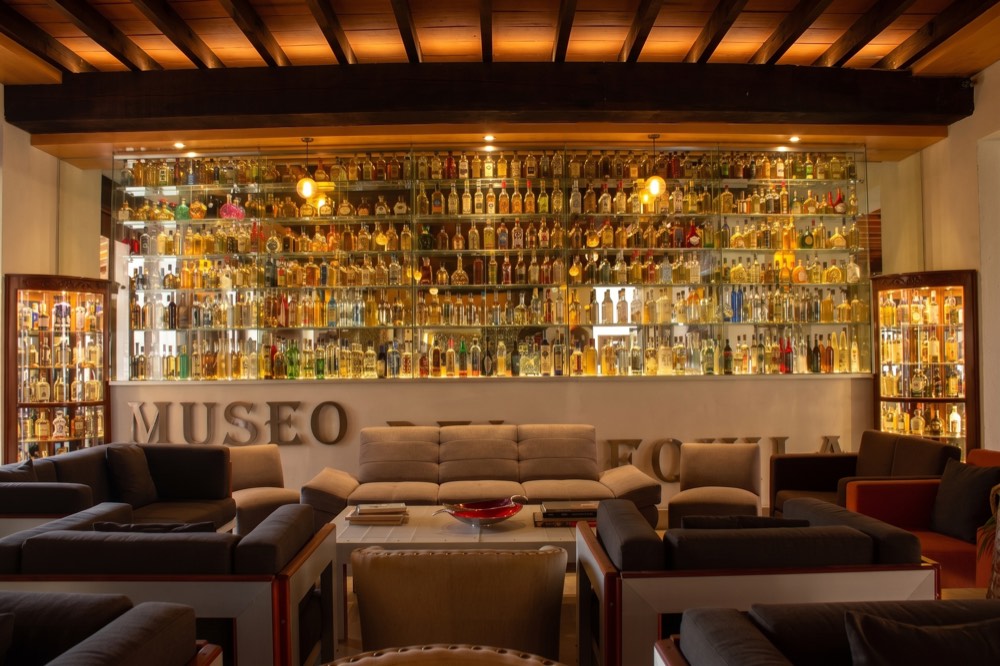 Área de estar del Museo del Tequila con exhibición de botellas y sillones