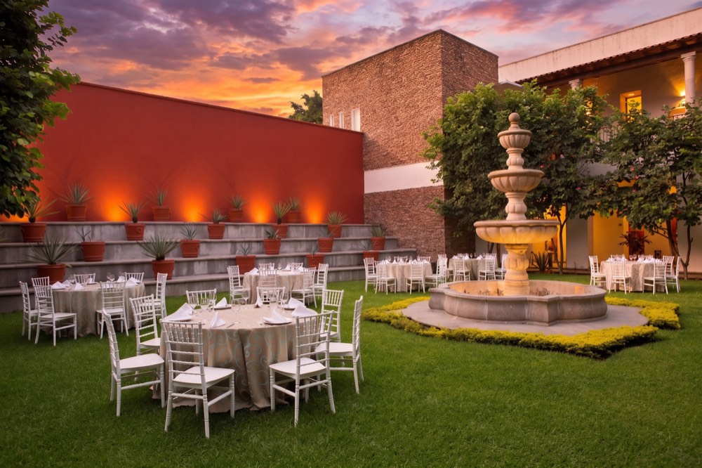 Terraza Agaves al atardecer con mesas redondas y fuente de cantera